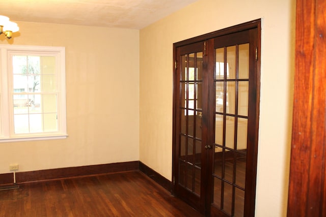 unfurnished room featuring dark wood-type flooring and a notable chandelier