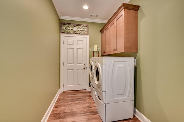 laundry room with cabinets, washing machine and dryer, ornamental molding, and light hardwood / wood-style floors