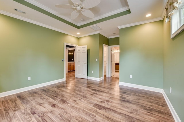 unfurnished bedroom with crown molding, ensuite bath, light wood-type flooring, a raised ceiling, and ceiling fan