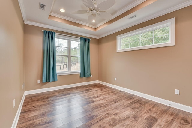 unfurnished room with ornamental molding, hardwood / wood-style floors, ceiling fan, and a tray ceiling