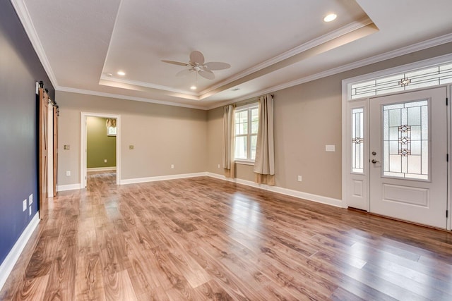 foyer featuring a raised ceiling, crown molding, and a barn door