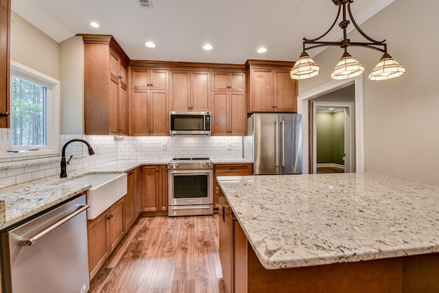 kitchen with light stone counters, high quality appliances, a kitchen island, and hanging light fixtures