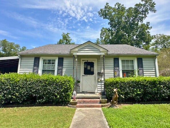 bungalow-style home with a front yard and a carport