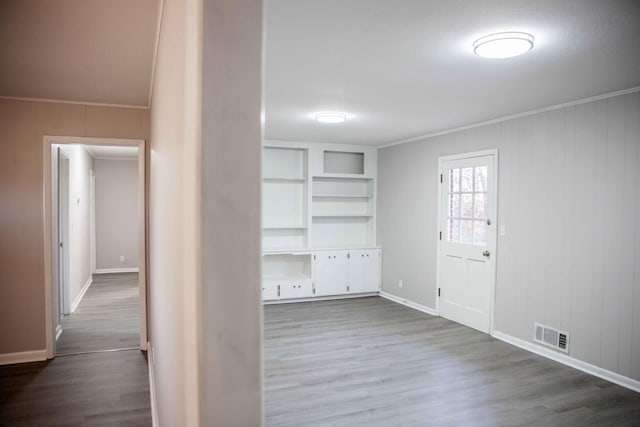 corridor featuring built in shelves, ornamental molding, and hardwood / wood-style floors