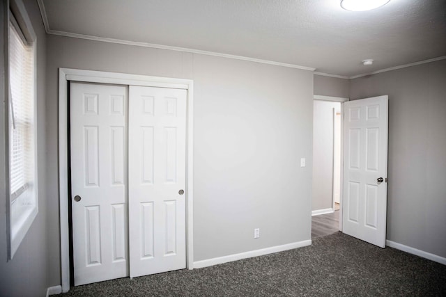 unfurnished bedroom with dark colored carpet, ornamental molding, and a closet