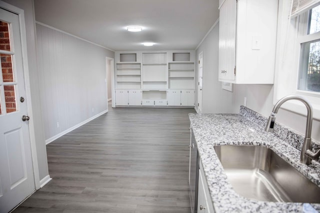 kitchen with light stone counters, crown molding, sink, and white cabinets