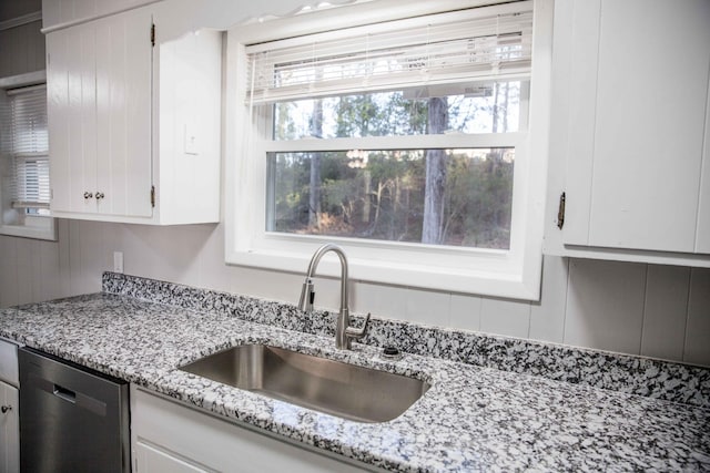 kitchen featuring white cabinetry, dishwasher, sink, and light stone countertops