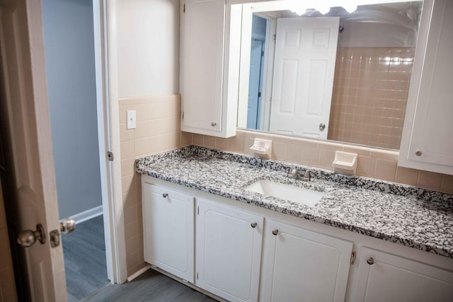 bathroom with vanity, wood-type flooring, and tile walls