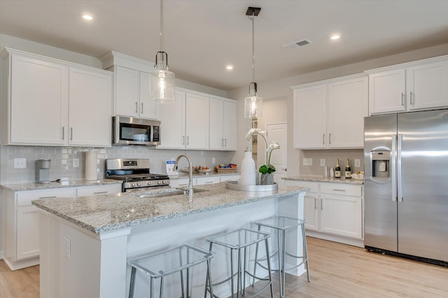 kitchen with sink, white cabinets, pendant lighting, and appliances with stainless steel finishes