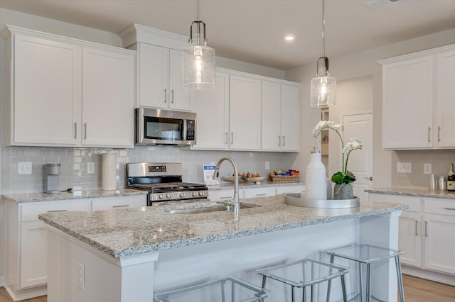 kitchen featuring white cabinets, sink, a center island with sink, and stainless steel appliances