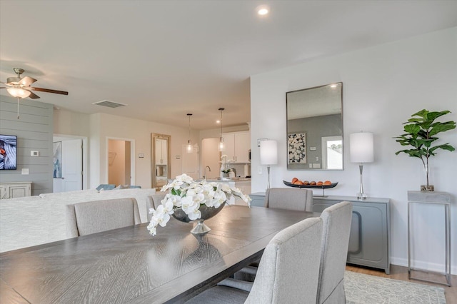 dining space featuring light wood-type flooring, ceiling fan, and sink