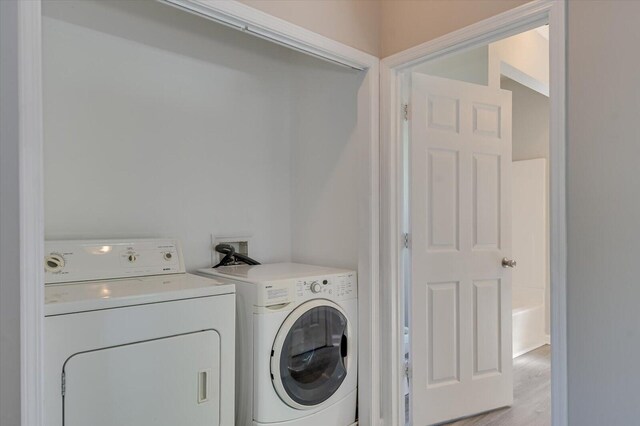 laundry room with light wood-type flooring, separate washer and dryer, and laundry area