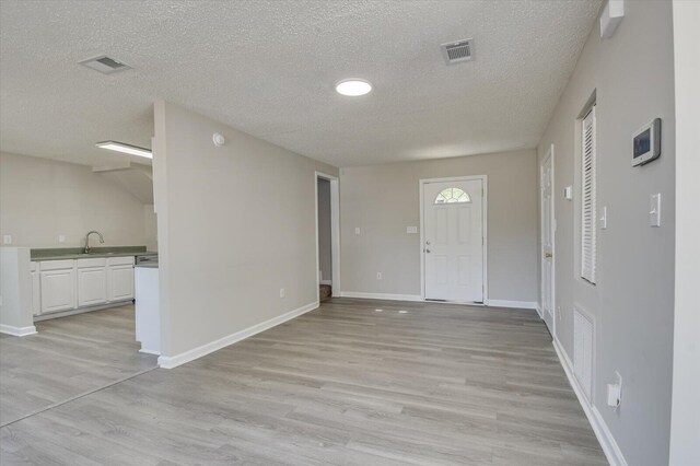 entryway with light wood finished floors, baseboards, and visible vents