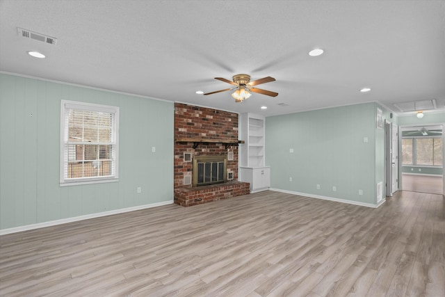 unfurnished living room with a brick fireplace, a textured ceiling, ceiling fan, and light hardwood / wood-style flooring