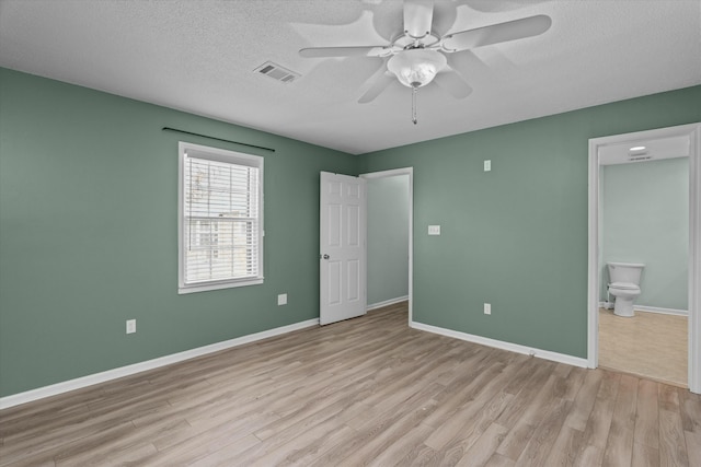 unfurnished bedroom with ceiling fan, ensuite bath, light hardwood / wood-style flooring, and a textured ceiling