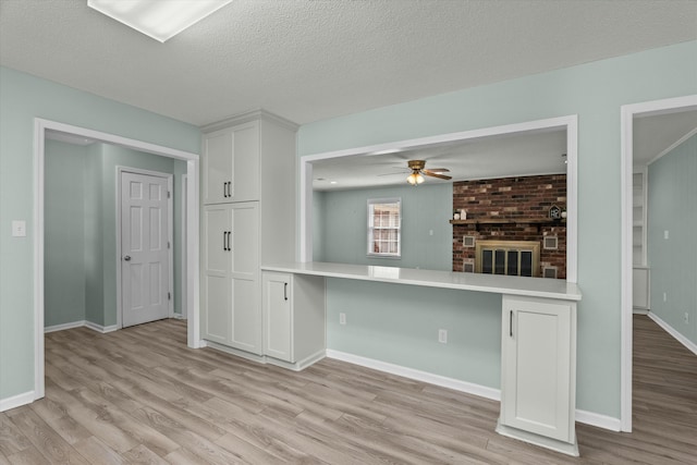 kitchen with built in desk, white cabinets, light wood-type flooring, and kitchen peninsula