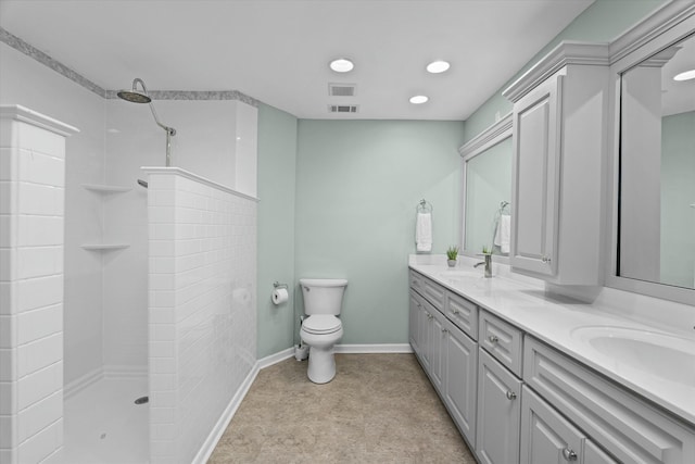 bathroom with tiled shower, vanity, and toilet