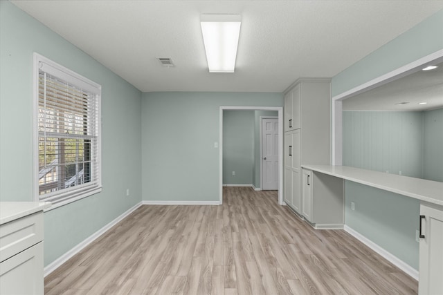 spare room with light hardwood / wood-style floors and a textured ceiling