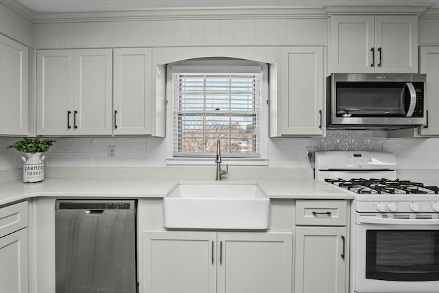 kitchen featuring appliances with stainless steel finishes, white cabinetry, sink, backsplash, and crown molding