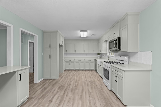 kitchen featuring white range with gas cooktop, sink, light hardwood / wood-style floors, and white cabinets