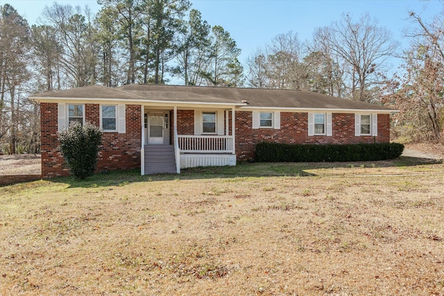 ranch-style home featuring covered porch and a front yard