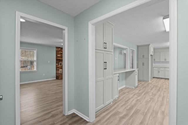 hall featuring light hardwood / wood-style flooring and a textured ceiling