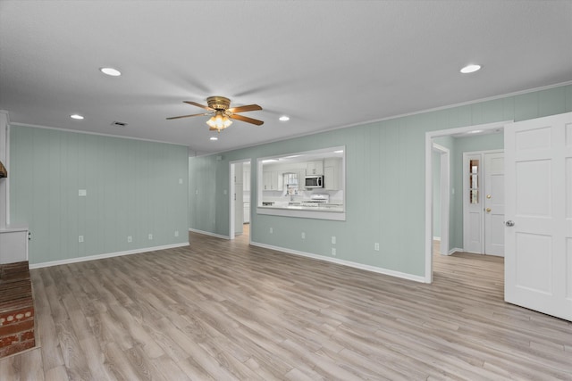 unfurnished living room featuring crown molding, ceiling fan, and light wood-type flooring