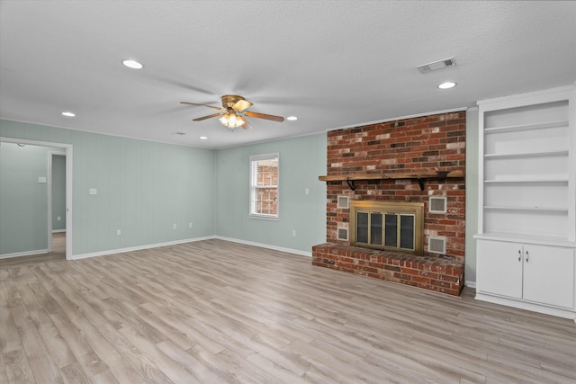 unfurnished living room featuring built in features, a fireplace, ceiling fan, a textured ceiling, and light hardwood / wood-style flooring