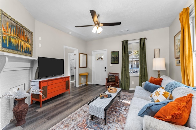 living room featuring a textured ceiling, ceiling fan, and dark wood-type flooring