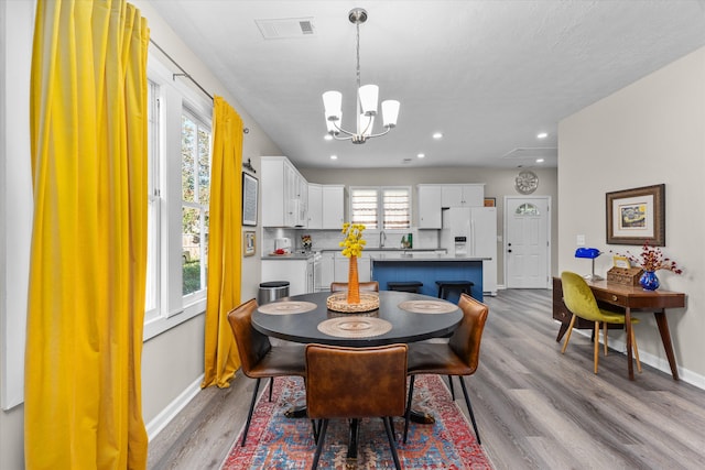 dining room with sink, a chandelier, and light wood-type flooring