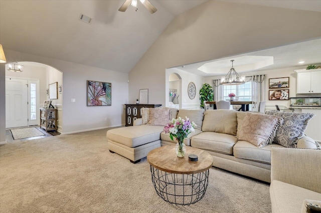 carpeted living room with ceiling fan with notable chandelier and vaulted ceiling