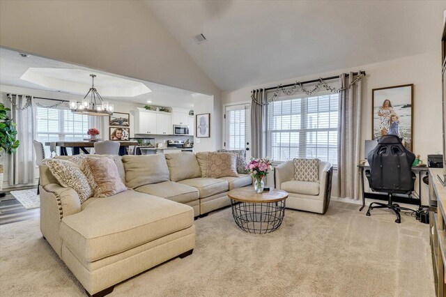 carpeted living room with a towering ceiling, a tray ceiling, and an inviting chandelier