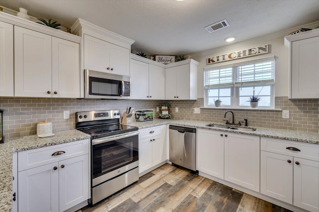 kitchen with white cabinets, appliances with stainless steel finishes, decorative backsplash, and sink