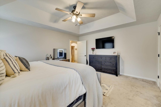 carpeted bedroom featuring a raised ceiling and ceiling fan