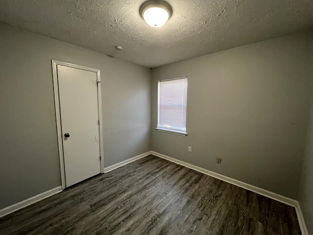 spare room featuring dark wood-type flooring and a textured ceiling