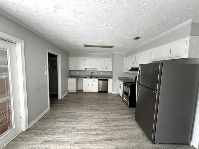 kitchen with sink, hardwood / wood-style flooring, a textured ceiling, white cabinetry, and stainless steel appliances