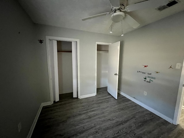 unfurnished bedroom with ceiling fan and dark wood-type flooring