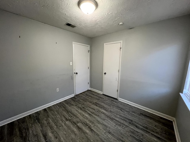 empty room featuring a textured ceiling and dark hardwood / wood-style floors