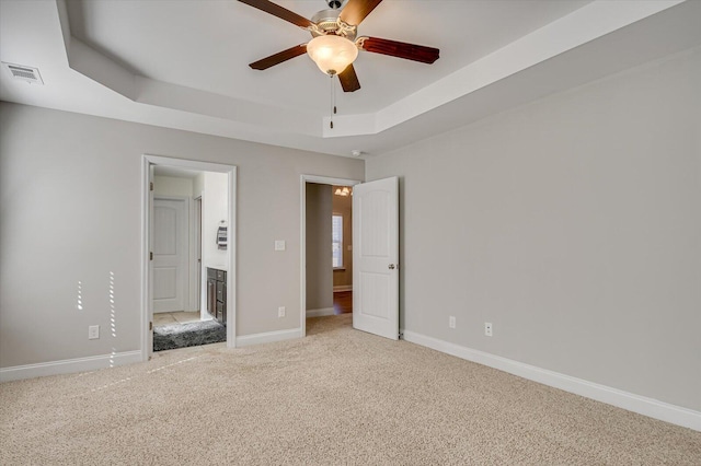 unfurnished bedroom with visible vents, connected bathroom, baseboards, carpet, and a tray ceiling