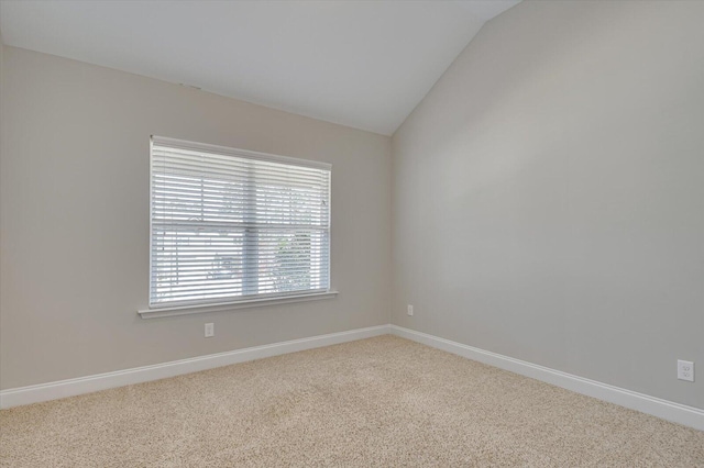 carpeted spare room with baseboards and vaulted ceiling