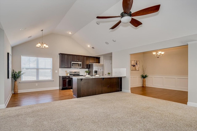 kitchen with a breakfast bar area, stainless steel appliances, dark brown cabinets, carpet flooring, and open floor plan