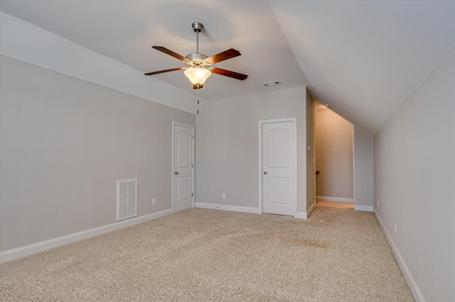 additional living space with visible vents, light colored carpet, baseboards, and vaulted ceiling