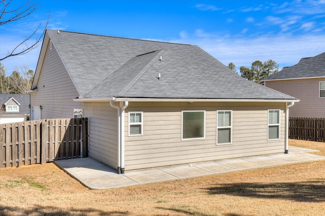 rear view of property featuring a yard, a fenced backyard, and a shingled roof