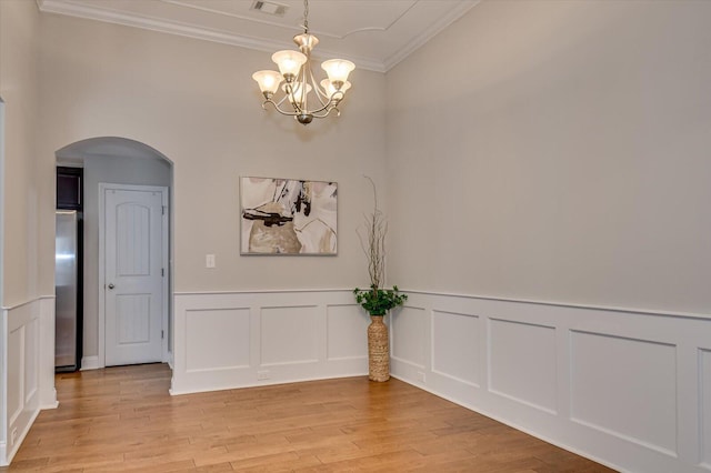 unfurnished dining area featuring visible vents, light wood finished floors, an inviting chandelier, arched walkways, and ornamental molding