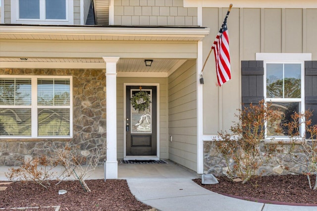 view of exterior entry with stone siding and a porch