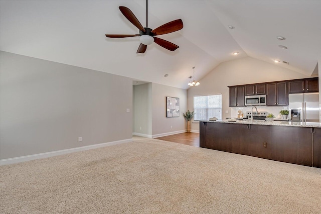 kitchen featuring light stone countertops, dark brown cabinetry, light carpet, ceiling fan with notable chandelier, and stainless steel appliances