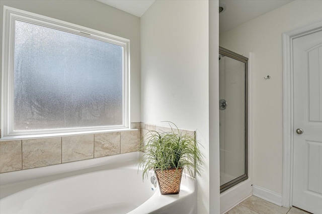 bathroom with a bath, a shower stall, and tile patterned flooring