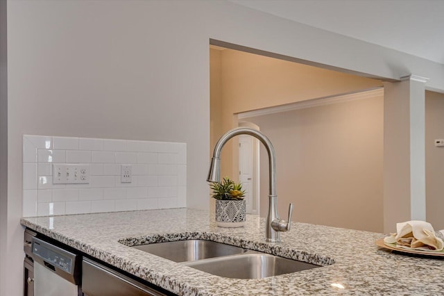 room details featuring light stone counters, dishwashing machine, tasteful backsplash, and a sink