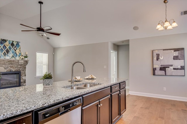 kitchen featuring light stone countertops, a fireplace, a sink, dishwasher, and decorative light fixtures