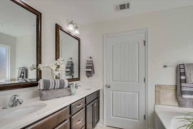 bathroom featuring a sink, visible vents, a bathtub, and double vanity